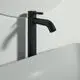 Waschtischarmatur in Schwarz von Ideal Standard, mit einem schlanken Design und einem Auslauf, montiert an einer hellen Wand über einem weißen Becken.